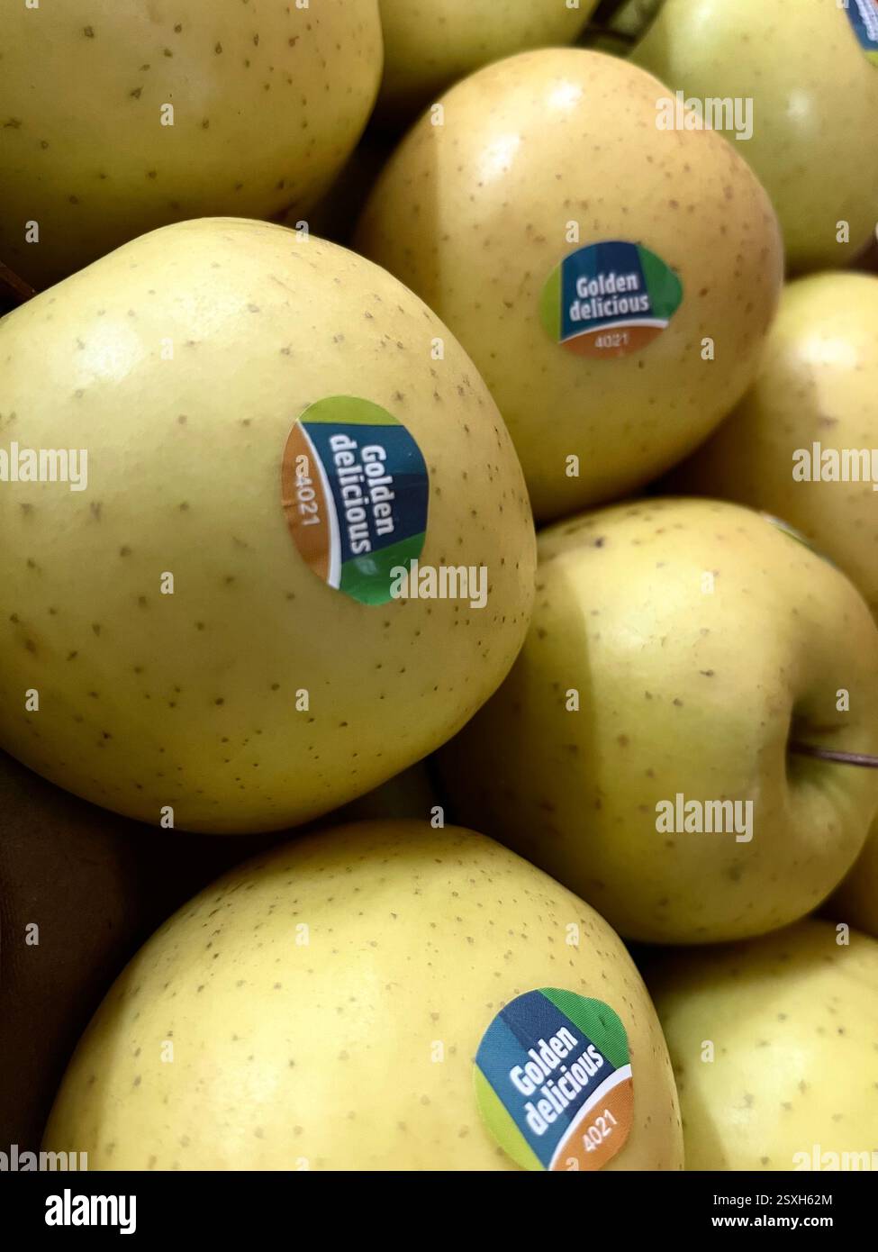 Mele etichettate con adesivi Golden Delicious con codice PLU 4021, esposte in un ambiente di vendita al dettaglio Foto Stock