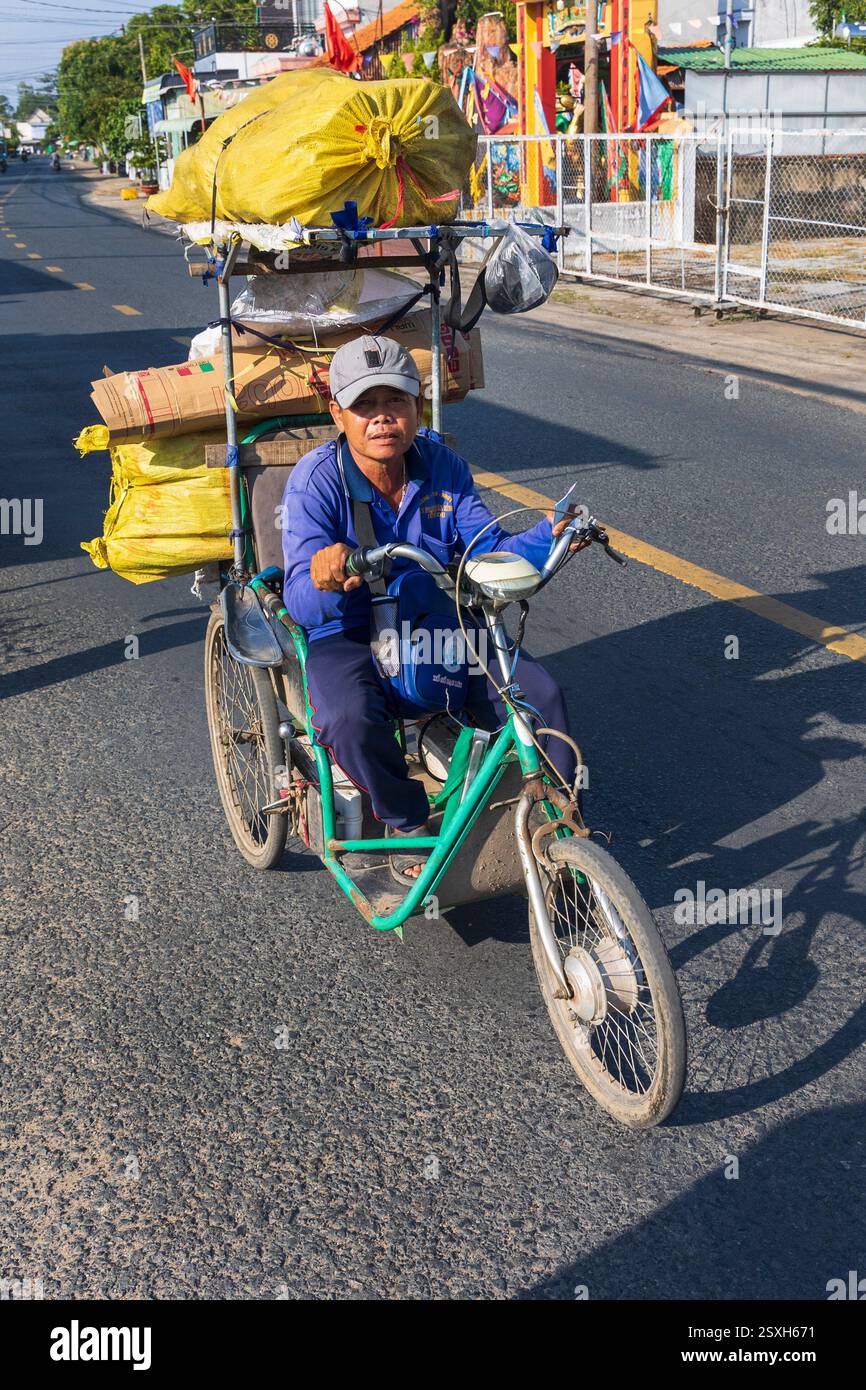 Un uomo in bicicletta carico di bene su una strada rurale in Vietnam, martedì 12 novembre 2024. Foto: David Rowland / One-Image.com Foto Stock