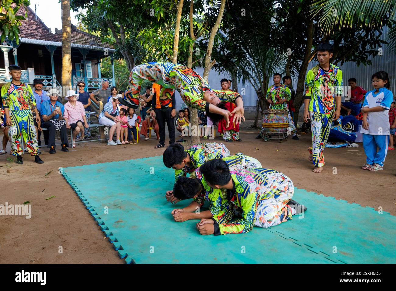 Nel villaggio di Long Thuan, in Vietnam, i ragazzi mostrano acrobazie impressionanti, catturando il pubblico con la loro agilità e costumi vivaci Foto Stock