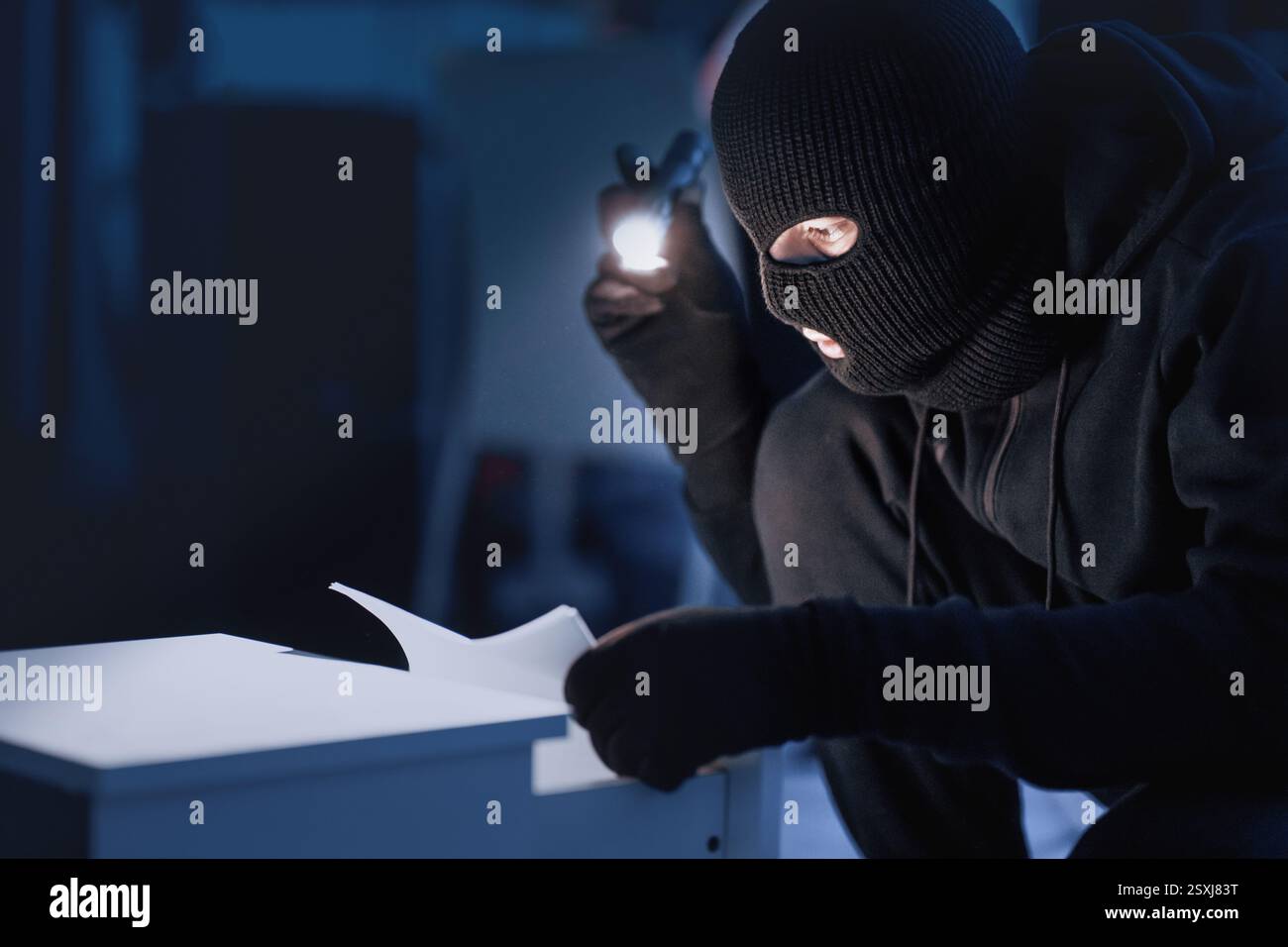Intruso mascherato che tiene e legge documenti riservati Foto Stock