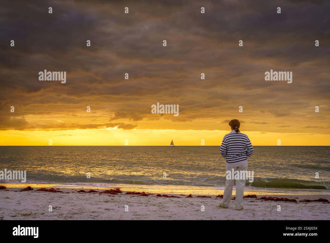 Una donna sta guardando il tramonto sulla spiaggia di Naples, Florida Foto Stock