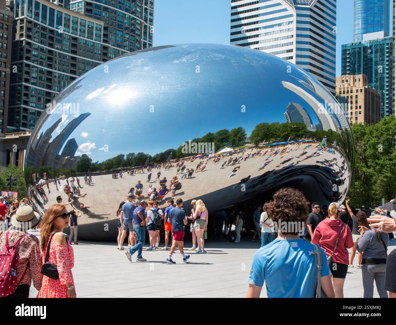 Chicago, Illinois, Stati Uniti - 18 luglio 2024: La folla si riunisce intorno a una grande scultura riflettente a Chicago, godendosi il sole e lo skyline della città. Foto Stock