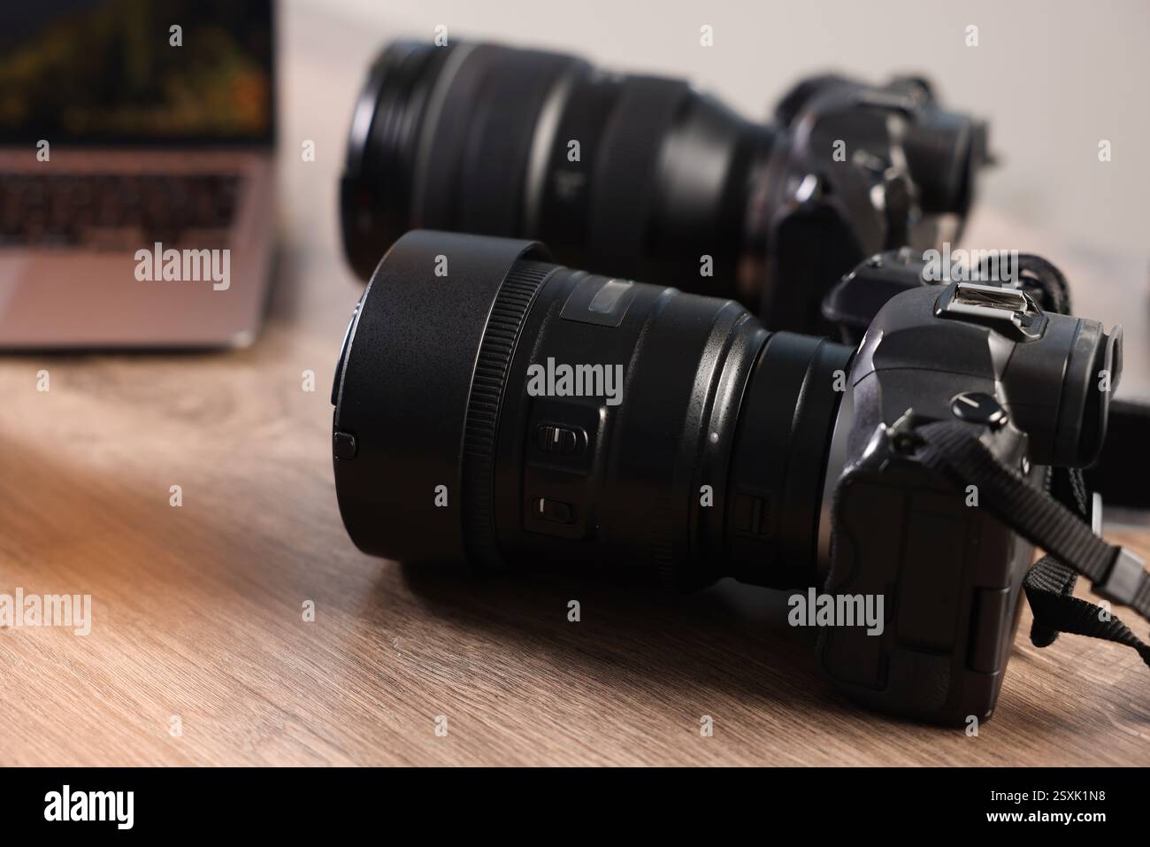 Fotocamere professionali e computer portatile su una scrivania in legno, primo piano Foto Stock
