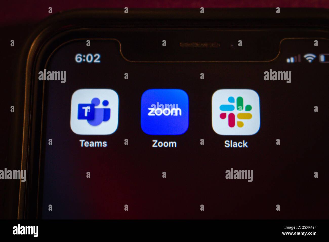 Le icone di Microsoft Teams, Zoom e Slack vengono visualizzate su un iPhone. Lavoro remoto moderno, strumenti di comunicazione e concetto di lavoro collaborativo. Foto Stock