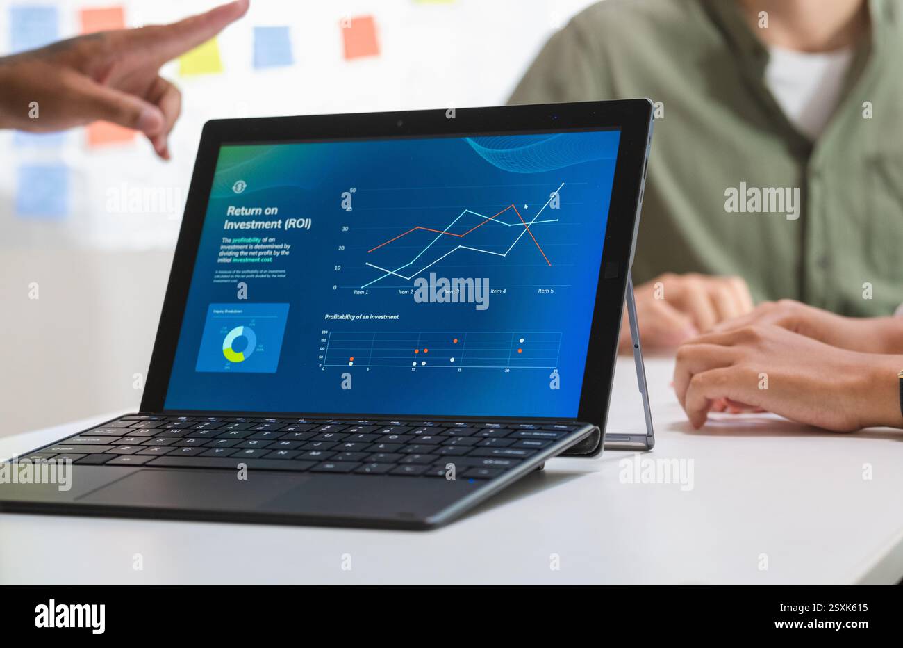 notebook quando presenta una presentazione aziendale in un ufficio scarsamente illuminato, analizzando grafici finanziari e proiezioni di dati su uno schermo Foto Stock