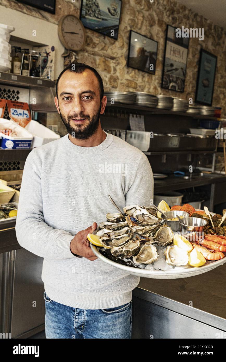 Cameriere che trasporta un piatto con ostriche e frutti di mare, Marsiglia, Francia, Europa Foto Stock