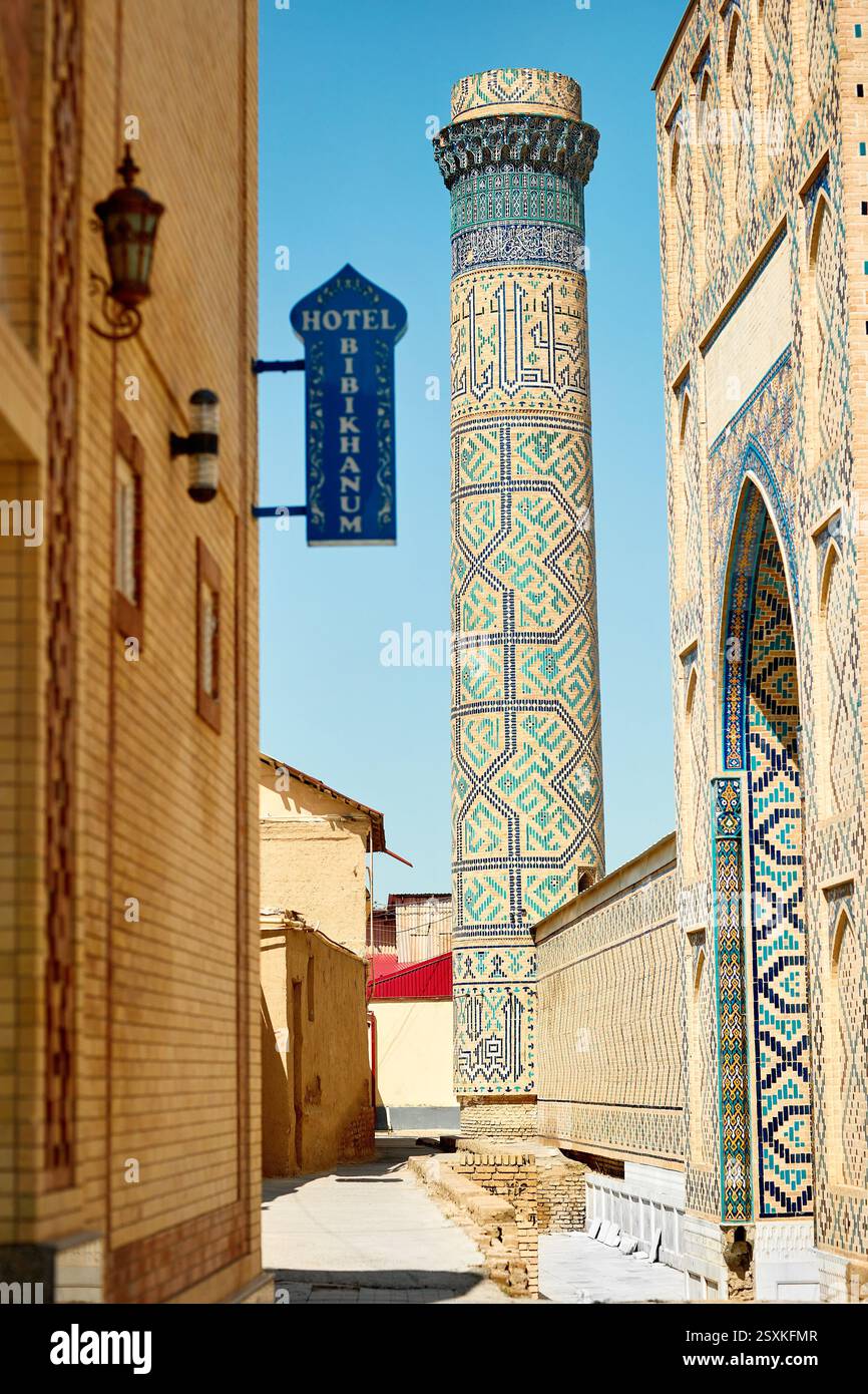 La torre del minareto si trova vicino all'hotel, in una strada stretta presso il complesso della moschea Bibi Khanum, contro il cielo blu di Samarcanda in Uzbekistan Foto Stock