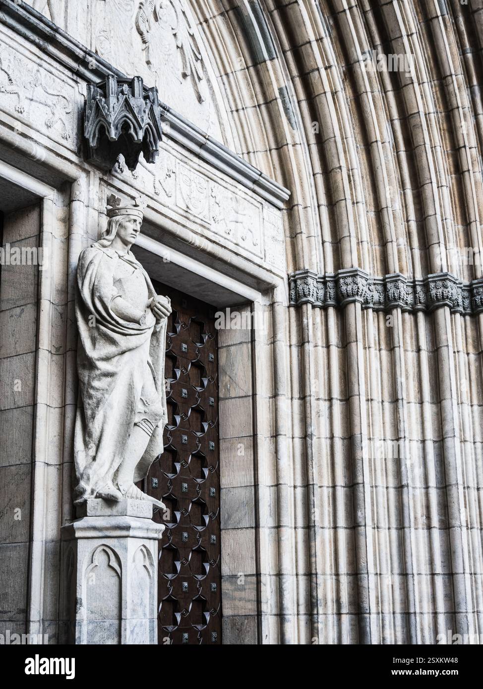 Una maestosa statua sorge all'ingresso della Chiesa di Uppsala, raffigurante una figura storica. L'intricato lavoro in pietra della facciata della chiesa sottolinea me Foto Stock