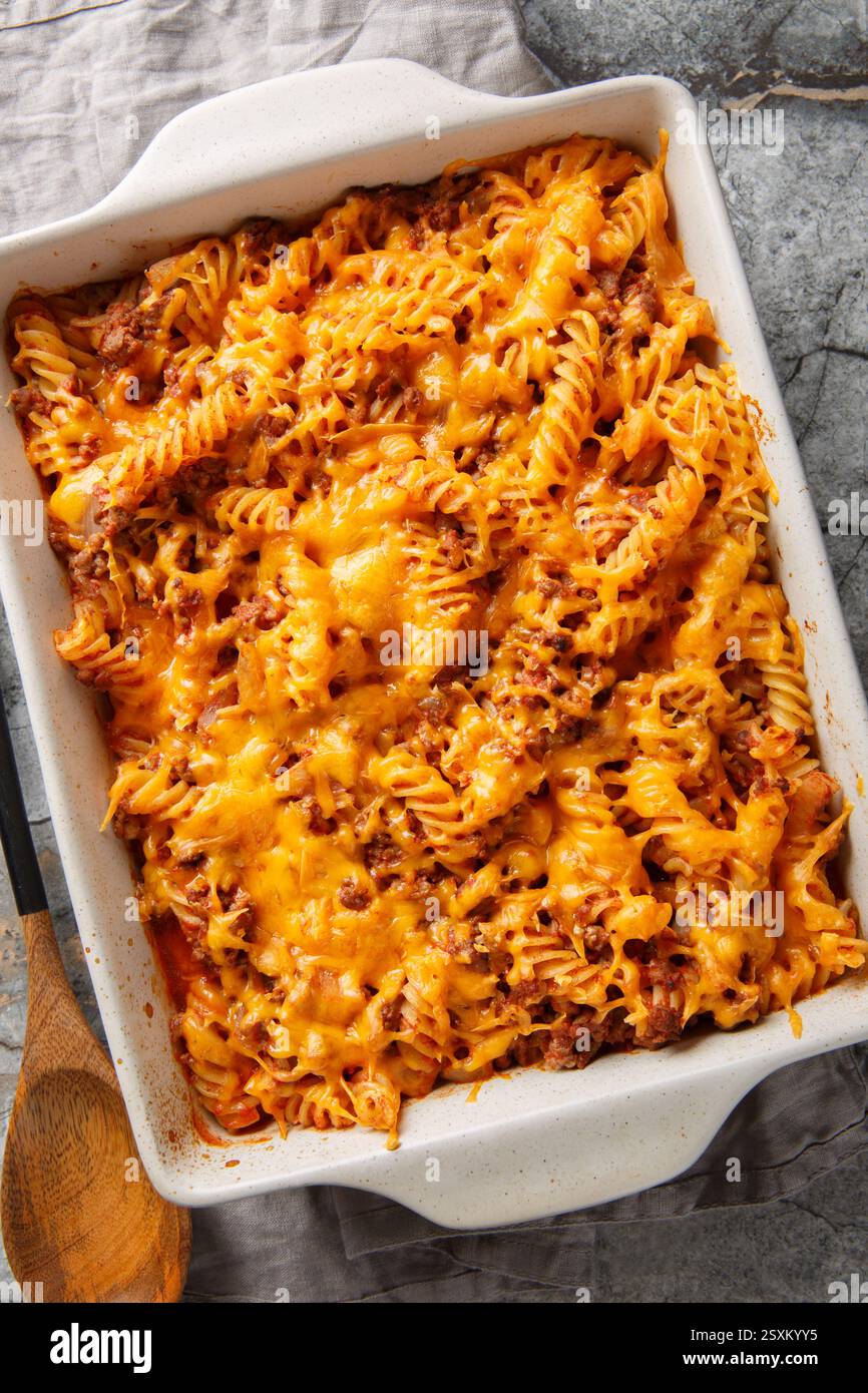 Casseruola Sloppy Joe preparata con pasta, un impasto di manzo macinato e un primo piano di formaggio grattugiato nel piatto da forno sul tavolo. Vista verticale dall'alto da Foto Stock