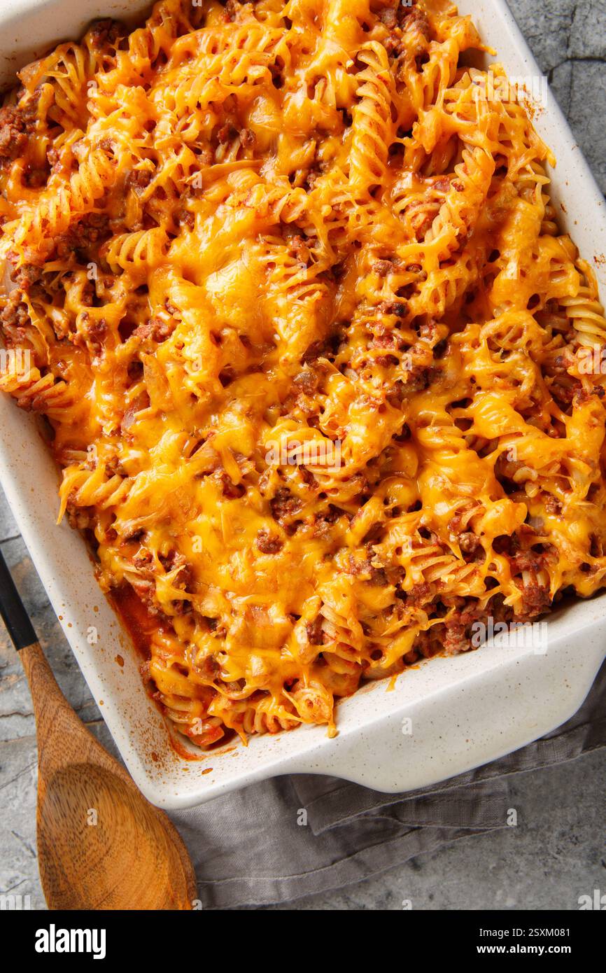 Deliziosa casseruola Sloppy joe con carne, pasta, verdure e salsa e un sacco di formaggio in primo piano nel piatto da forno sul tavolo. Vista dall'alto verticale da abov Foto Stock
