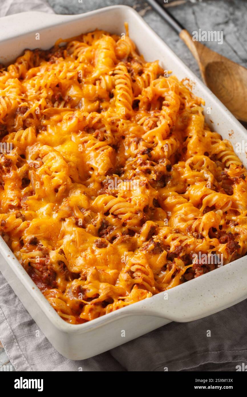 Casseruola Sloppy Joe preparata con pasta, un impasto di manzo macinato e un primo piano di formaggio grattugiato nel piatto da forno sul tavolo. Verticale Foto Stock