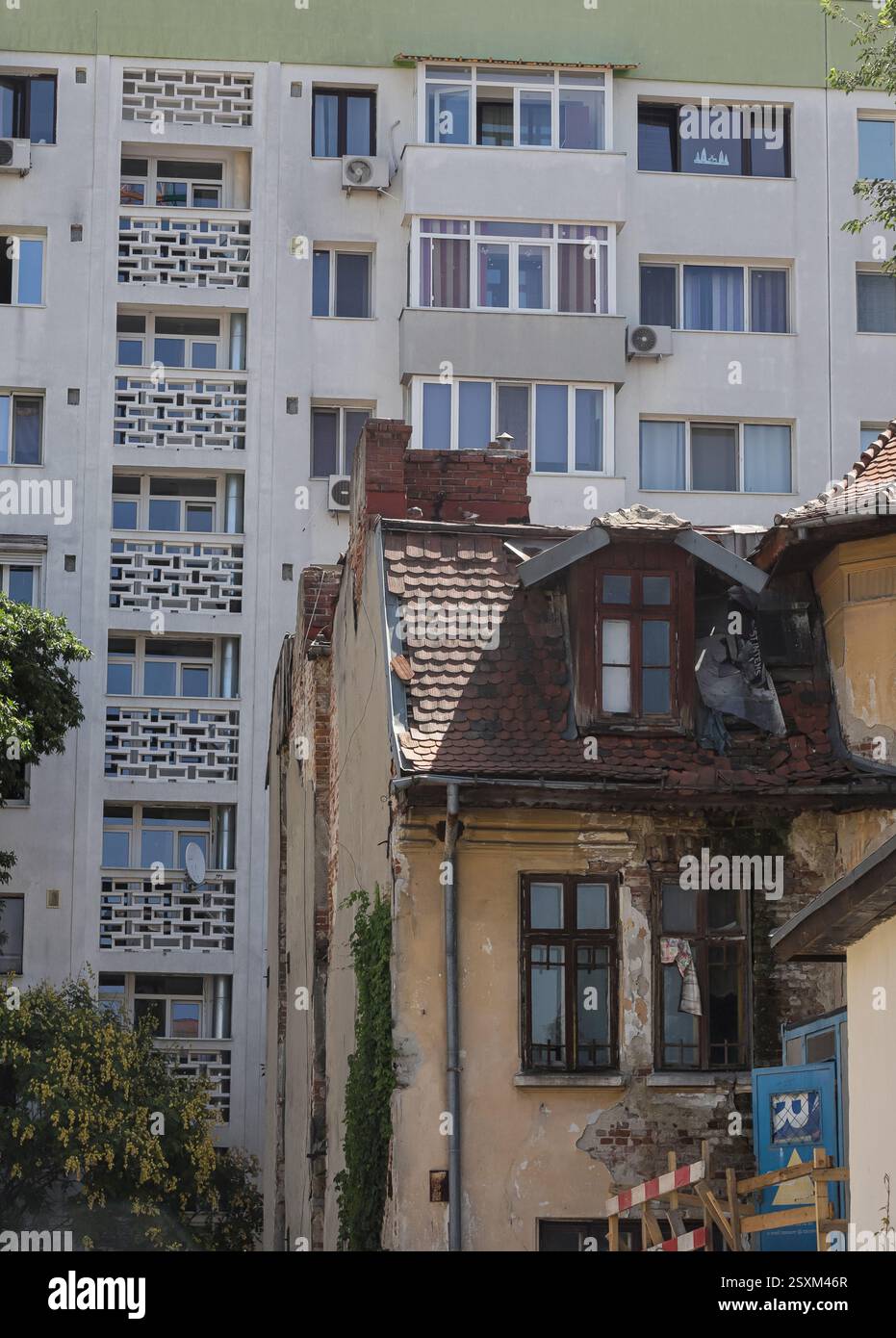 Una miscela di architettura vecchia e nuova a Bucarest mostra le differenze tra un edificio storico in deterioramento e un moderno complesso di appartamenti nelle vicinanze Foto Stock
