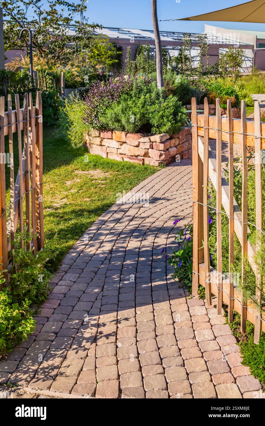 Ingresso al moderno orto con letti in mattoni rialzati. Aiuole rialzate che giardinano in un giardino urbano dove si coltivano piante e verdure Foto Stock