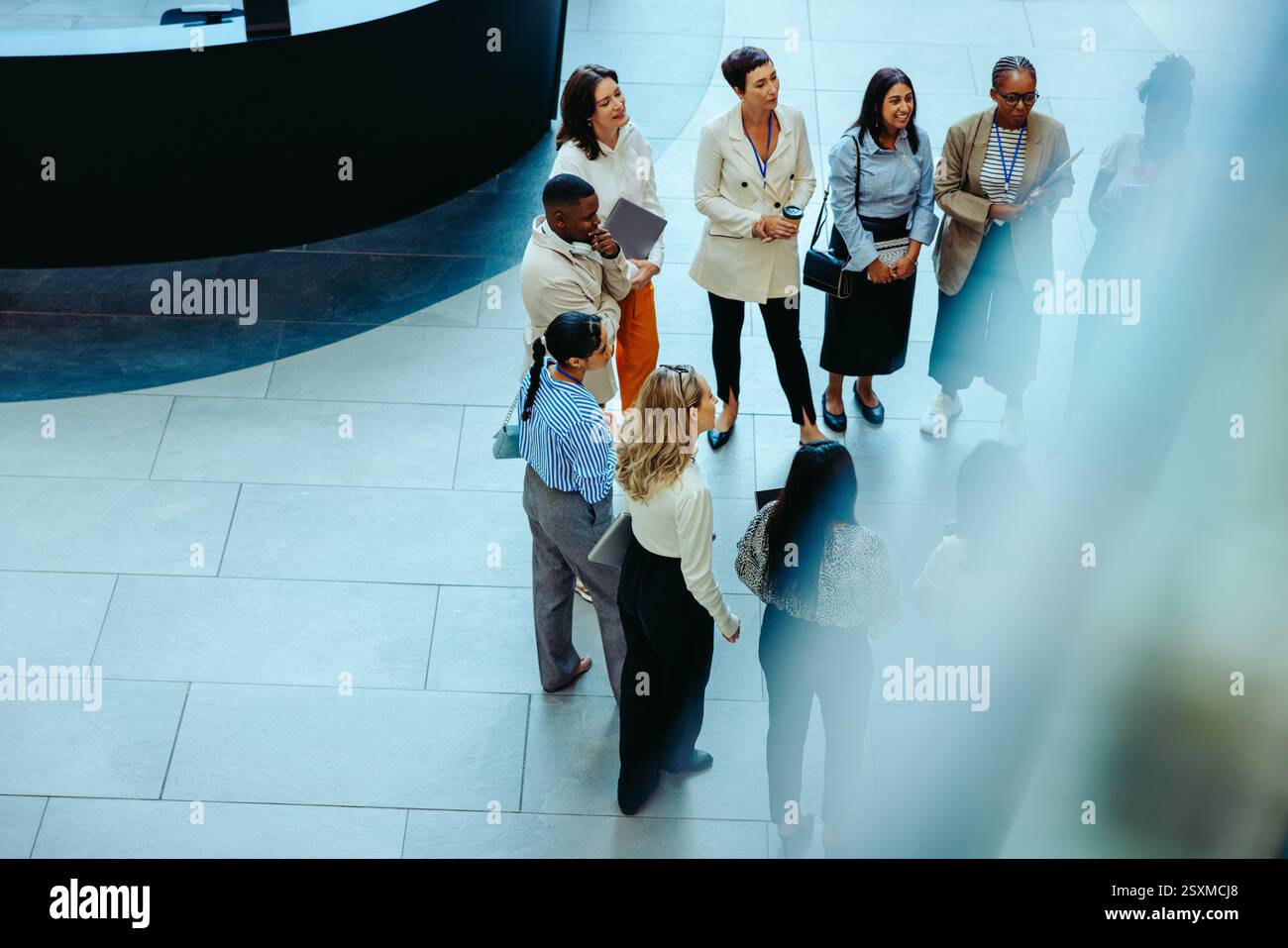 Un team diversificato di colleghi si è riunito in una lobby aziendale presso una società di contabilità, concentrandosi su audit, consulenza e sviluppo professionale Foto Stock