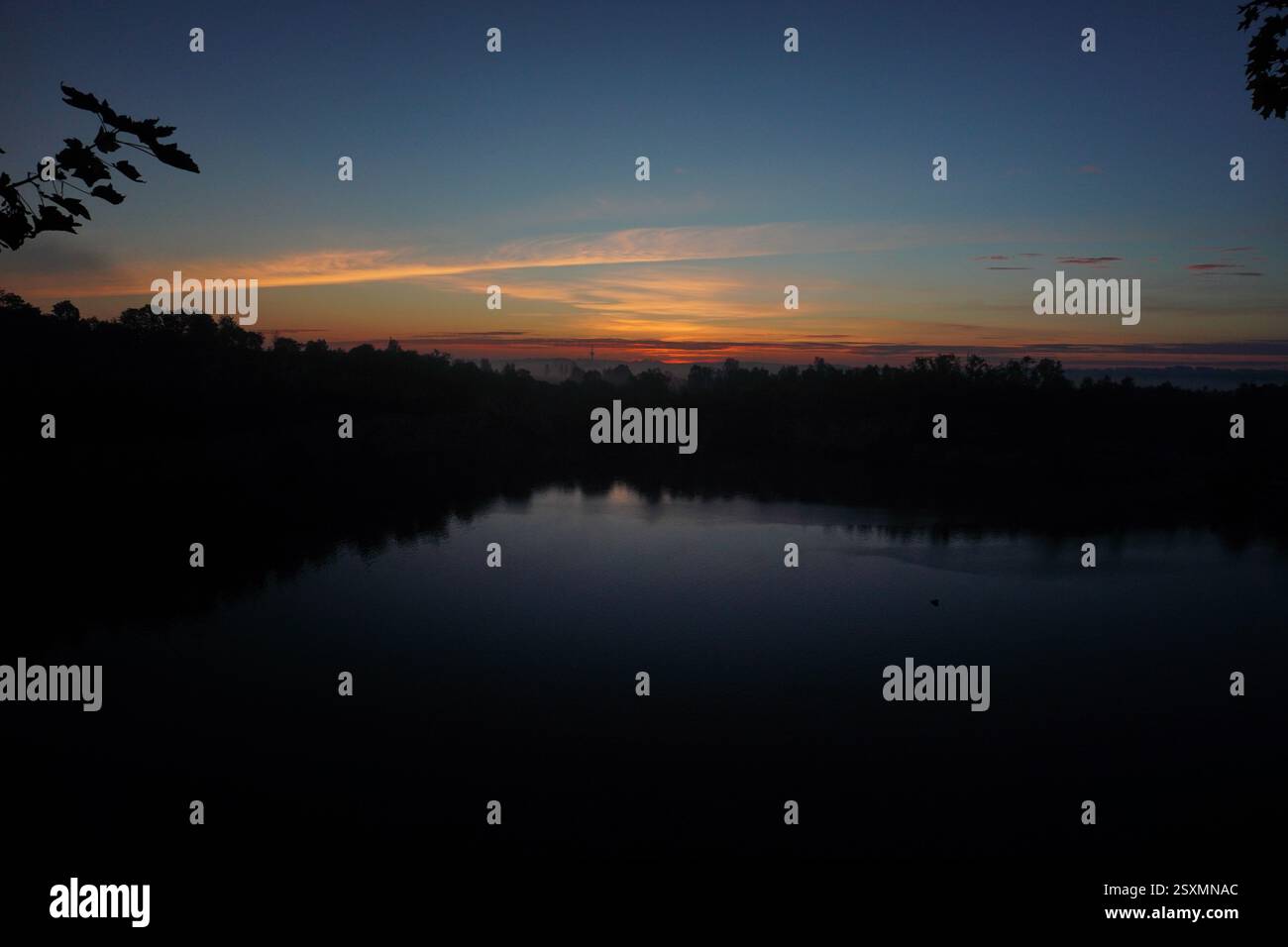 L'alba autunnale vicino al lago del parco in città, il cielo colorato si specchia nell'acqua. Nebbia sopra l'acqua. messa a fuoco selettiva Foto Stock