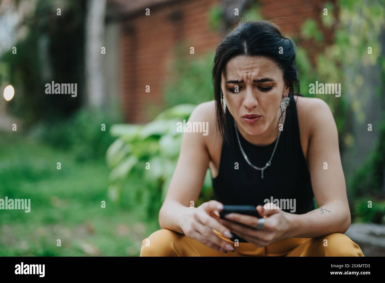 Donna all'aperto che sembra frustrata mentre controlla i messaggi sul telefono Foto Stock