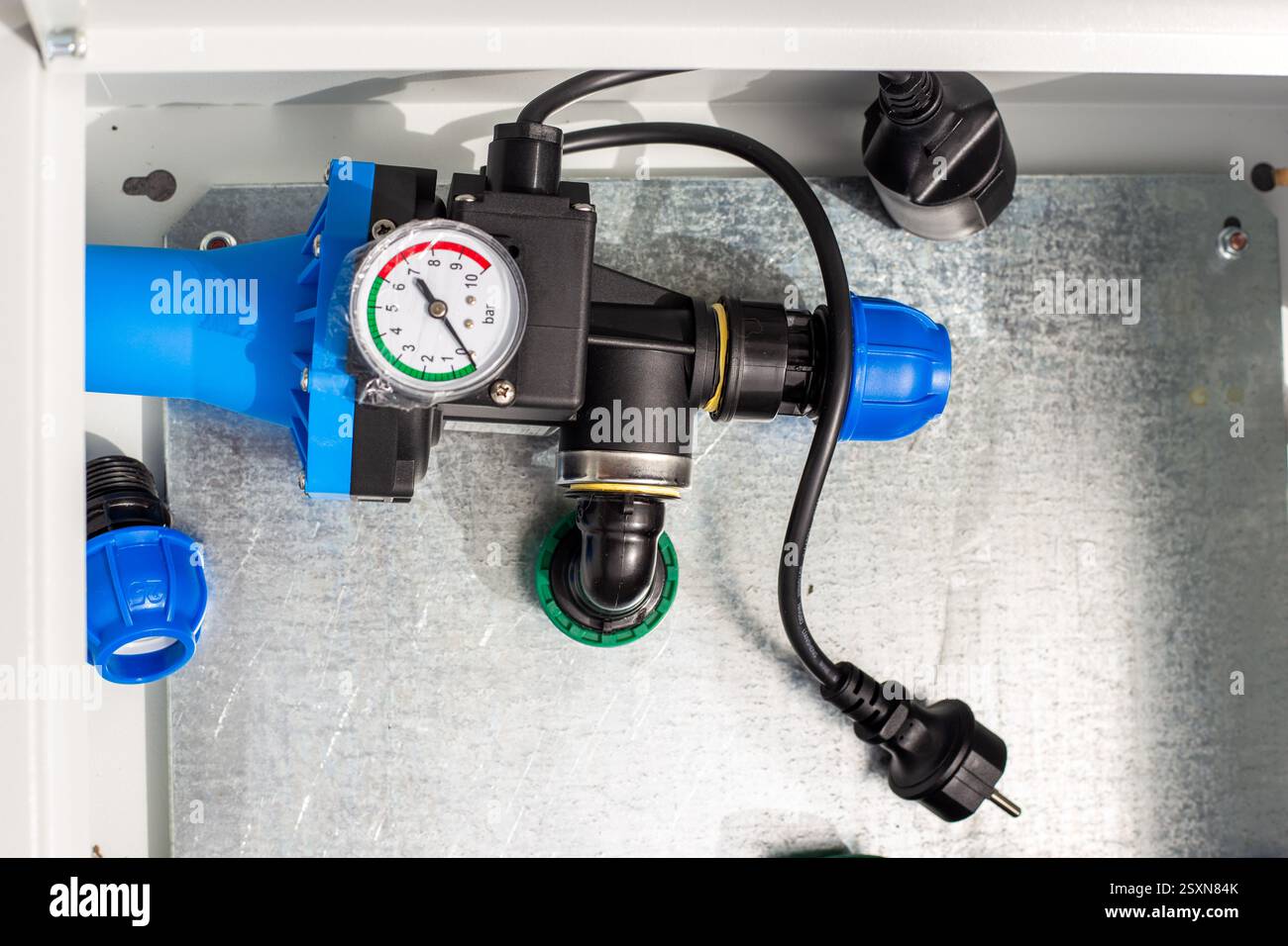 Regolatore automatico dell'alimentazione dell'acqua con manometro in una scatola di metallo. Installazione del sistema di irrigazione a goccia. Foto Stock