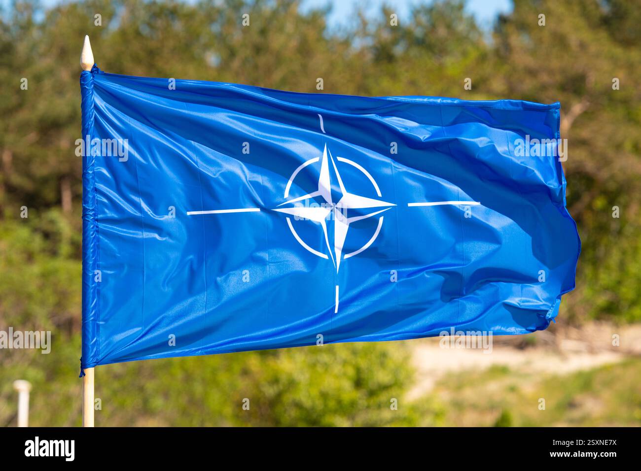 Bandiera con simbolo di rinuncia NATO su uno sfondo verde sfocato Foto Stock