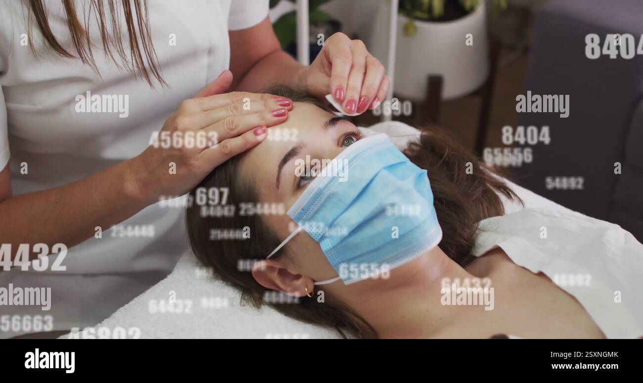 Ricevendo trattamento viso, donna che indossa maschera con immagini sovrapposte di numeri Foto Stock