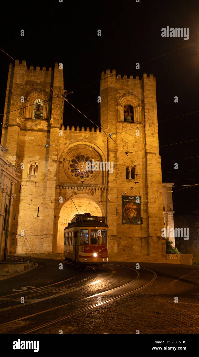 Un tram passa di fronte alla Cattedrale di se di notte ad Alfama, la sezione della città vecchia di Lisbona. Foto Stock