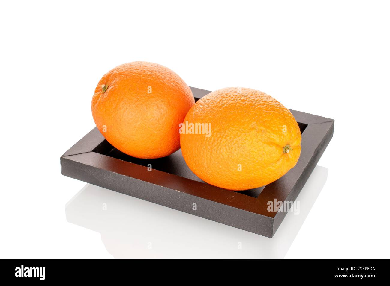 arance mature su un vassoio di legno nero, primo piano, isolato su sfondo bianco. Foto Stock