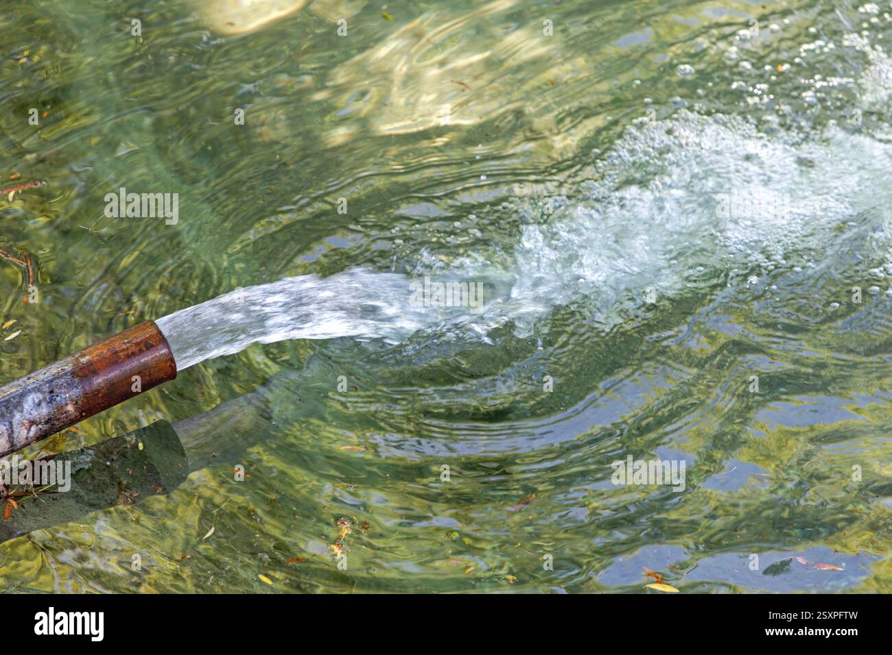 Flusso del tubo ad alta pressione dell'acqua pulita nel laghetto verde Foto Stock