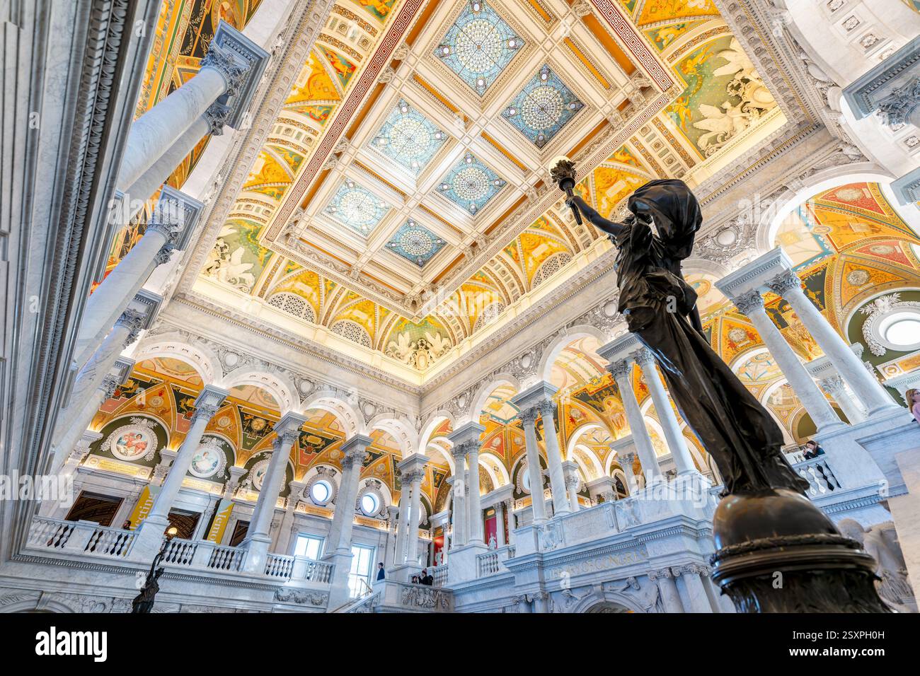 WASHINGTON DC - Una statua di bronzo di una figura femminile che tiene in alto una torcia elettrica si trova su un palo di newel nella sala principale della Biblioteca del Congresso Thomas Jefferson Building. Completata nel 1897, la figura femminile decorativa in bronzo simboleggia l'innovazione tecnologica americana nell'elettricità. La statua fa parte della decorazione ornata della grande scalinata in marmo nella sala grande e celebra i contributi americani alla scienza, in particolare la scoperta dell'elettricità di Benjamin Franklin, che ha permesso innovazioni come l'illuminazione elettrica prominente in tutto l'edificio. Foto Stock