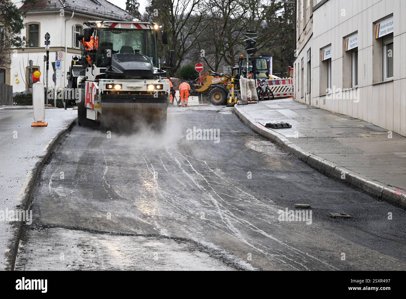 Stoccarda, Germania. 25 febbraio 2025. Un rullo leviga e comprime la superficie stradale appena applicata in un cantiere di rinnovo stradale. Crediti: Bernd Weißbrod/dpa/Alamy Live News Foto Stock