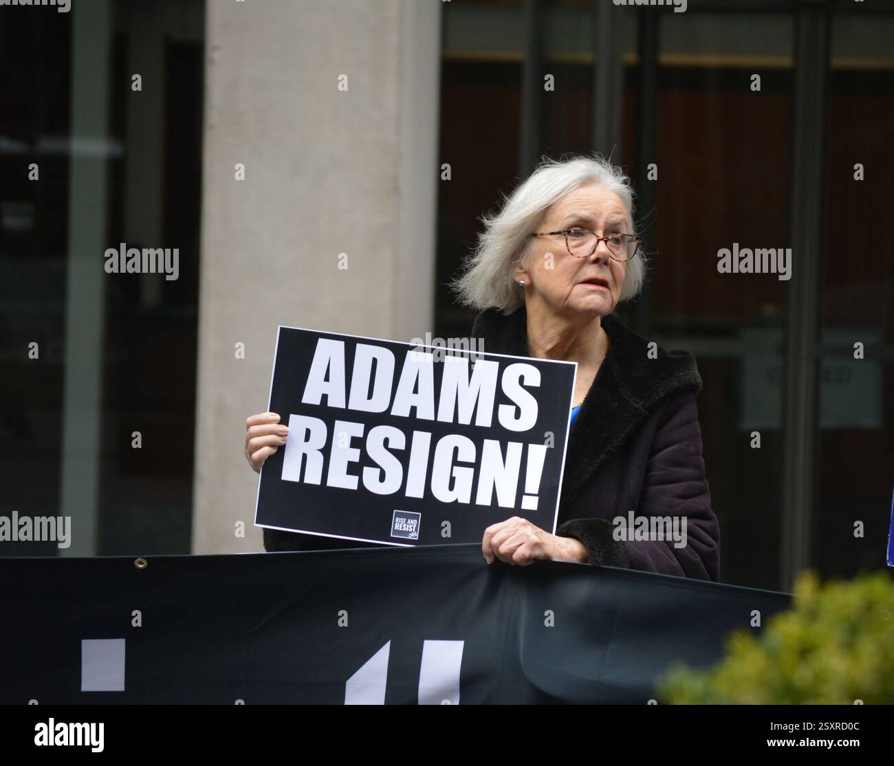 Manifestante con un cartello che chiede al sindaco di New York Eric Adams di dimettersi a Midtown Manhattan. Foto Stock