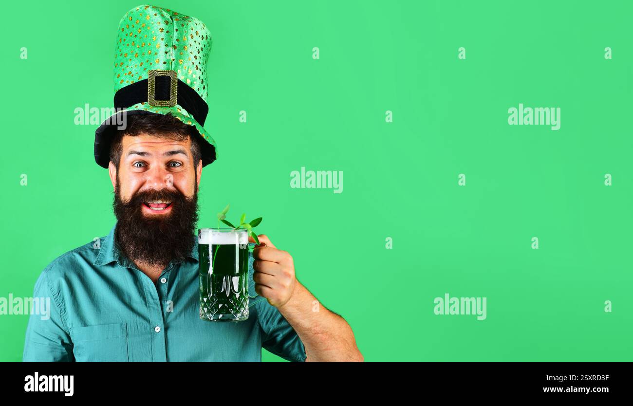 Festa al pub Patrick Day. Uomo barbuto felice con camicia verde e cappello che beve birra verde. Tradizione irlandese. L'uomo barbuto in cappello da leprechaun regge di tazza Foto Stock