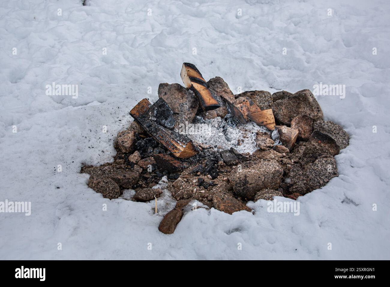 Un fuoco da campeggio è stato spento ed è freddo nelle condizioni nevose. Foto Stock