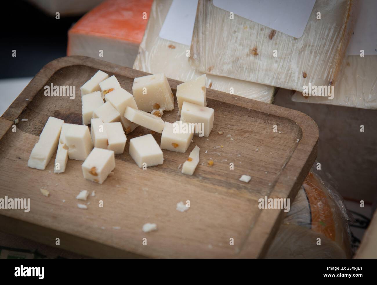 Piccoli cubetti di formaggio con noci su tavola di legno esposti presso la banchina del mercato che offrono una varietà di prodotti caseari da assaggiare Foto Stock