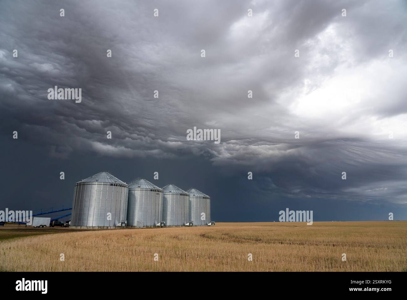 Nuvole di tempesta minacciose che si formano sui silos di grano in un campo di grano Foto Stock