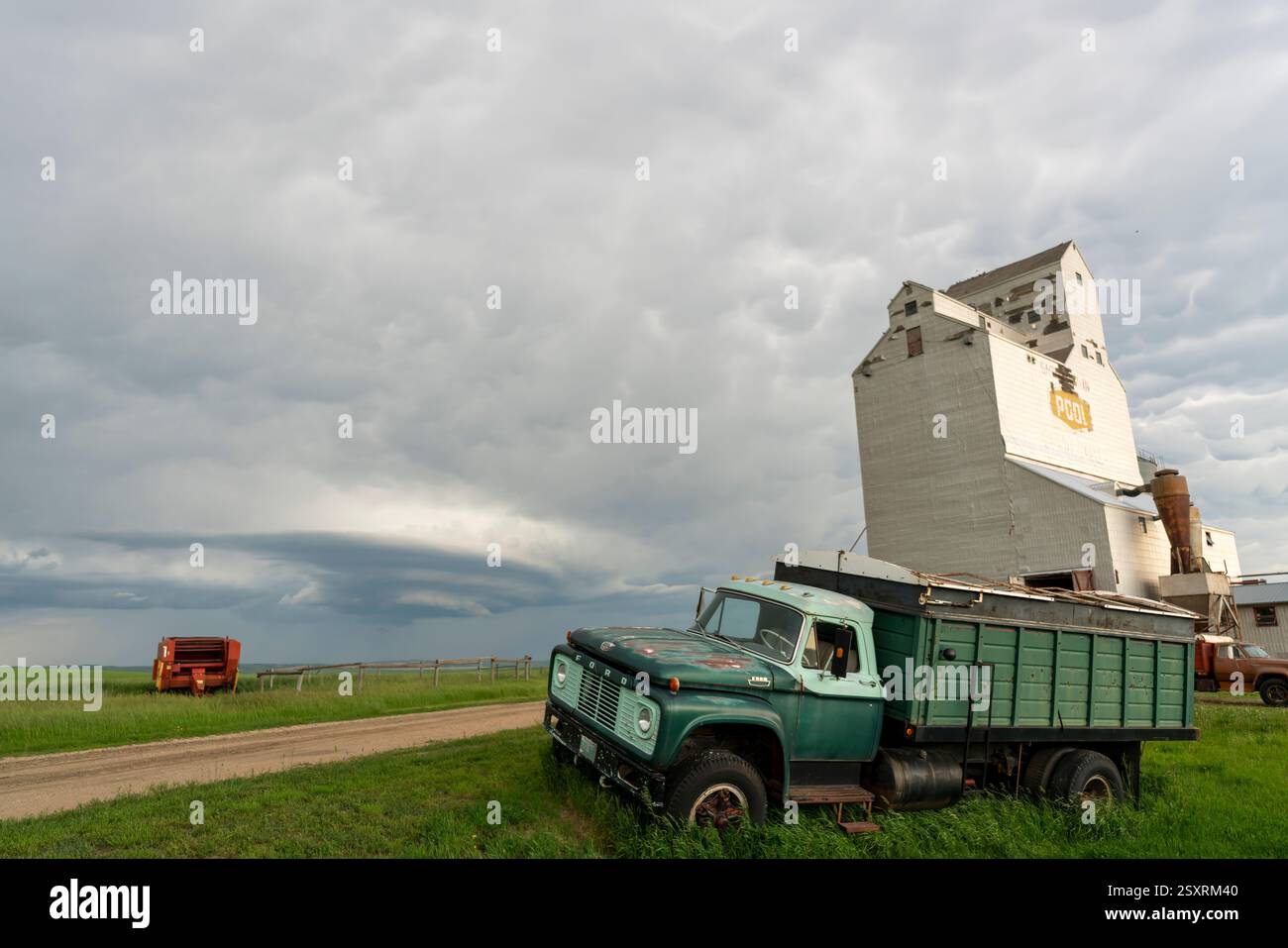 Camion d'epoca parcheggiato vicino a un ascensore con un cielo tempestoso sullo sfondo, nelle praterie canadesi Foto Stock