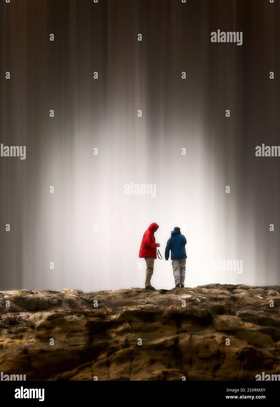 Due fotografi ammirano seljalandsfoss, una maestosa cascata in islanda, conosciuta per il percorso che consente di camminare dietro di essa Foto Stock