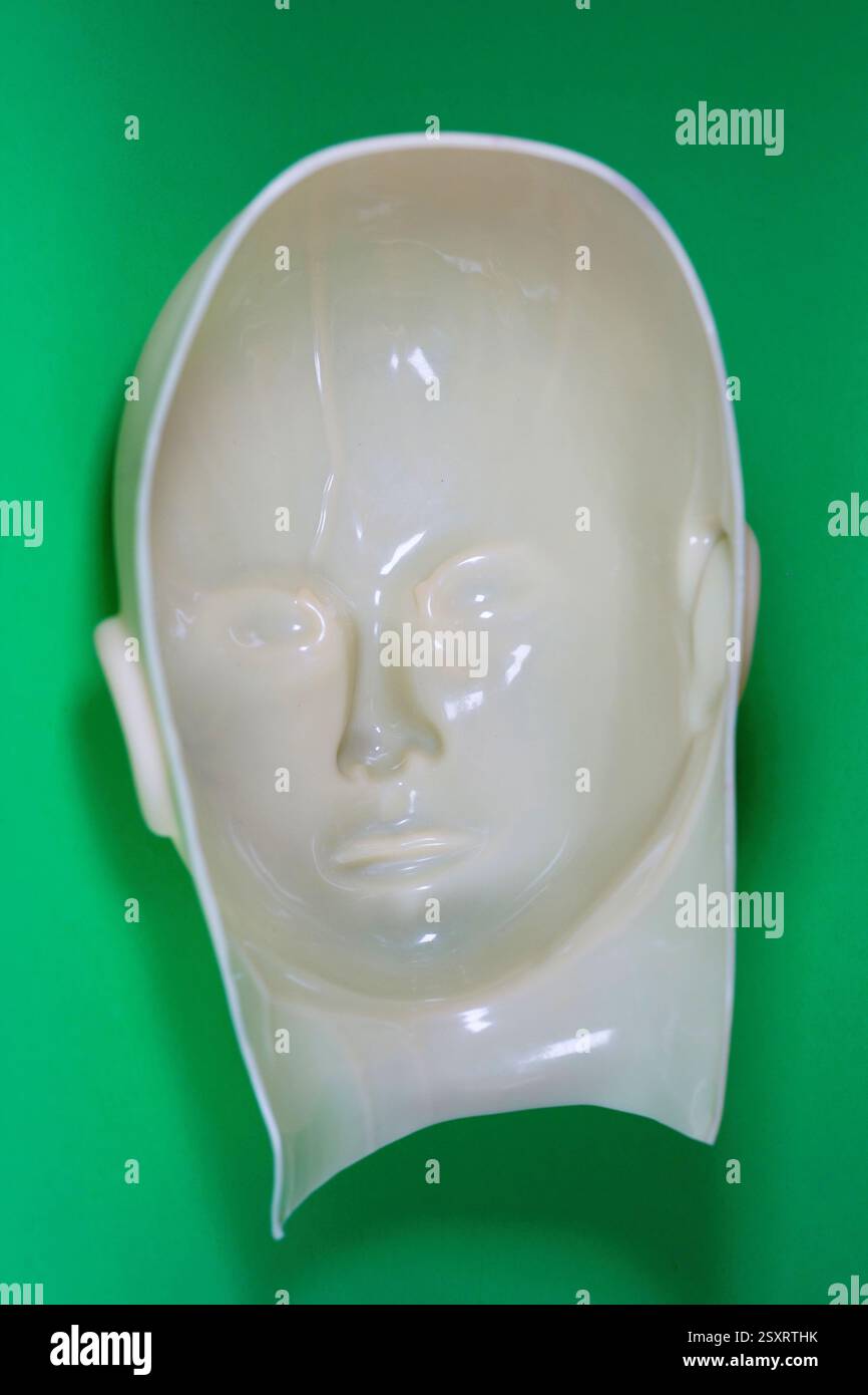 Un surreale che guarda dentro fuori fuori maschera di gomma su sfondo verde. Foto Stock