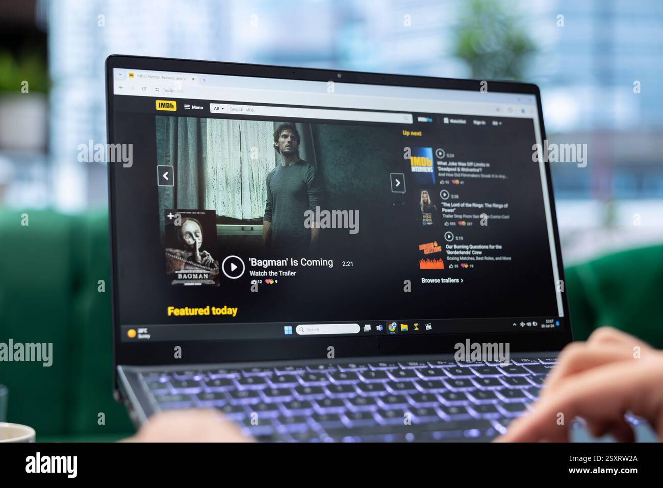 Bucarest, Romania - 30 luglio 2024 - i giovani adulti scorrono la homepage di IMDb per trovare un film da guardare basato su giudizi e critici metascore. Uomo Cinefilo che controlla la lista degli attori in ufficio. Foto Stock