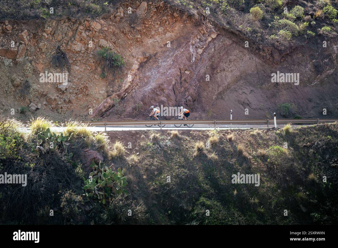 Ciclisti su una strada di montagna tra un paesaggio roccioso Foto Stock