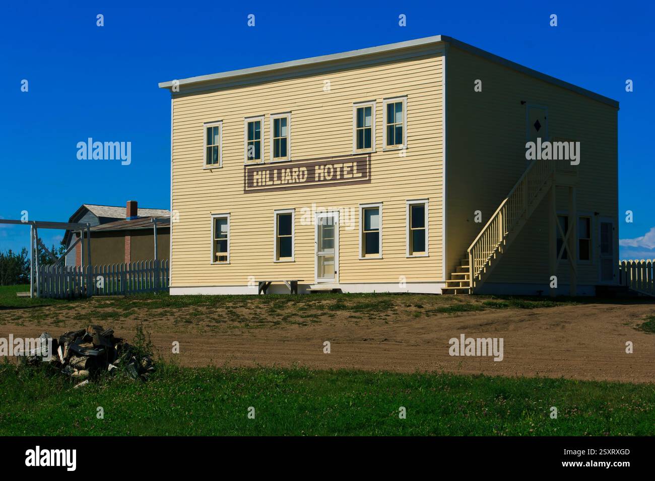 Edificio giallo con il nome di Hillard Hotel. L'edificio è circondato dall'erba. Di fronte all'edificio c'è una recinzione di legno Foto Stock