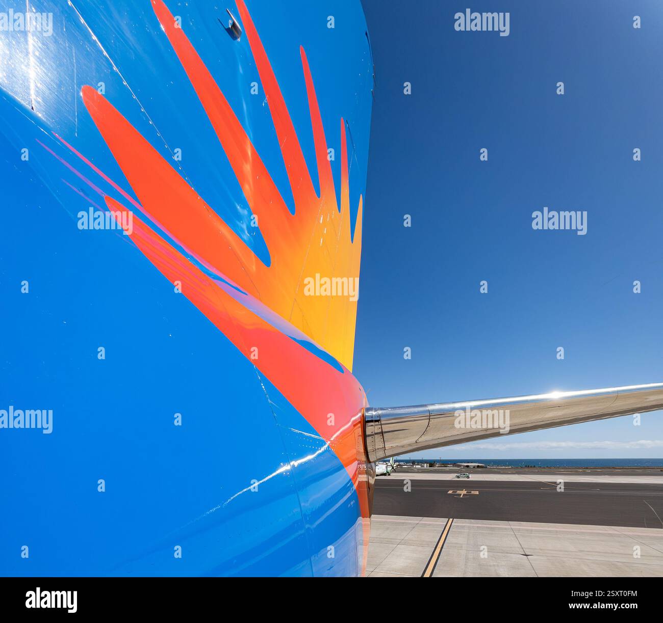 Primo piano di una vivace coda di un aereo con un sorprendente design blu e arancione Sunburst sotto un cielo azzurro. Jet2 all'aeroporto di Lanzarote. Foto Stock