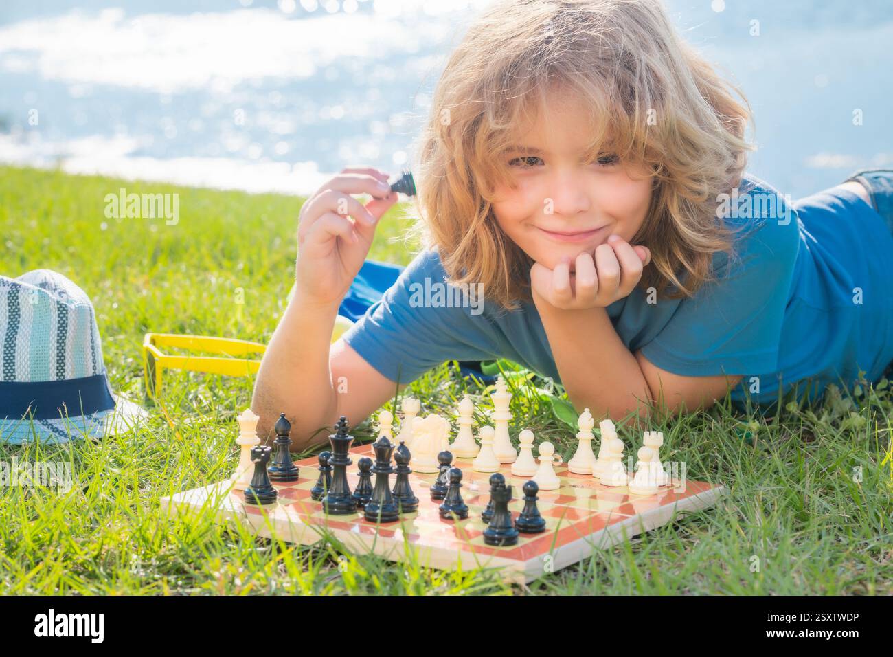 Il ragazzo mostra i pezzi degli scacchi su una scacchiera. Un bambino intelligente concentrato e pensante che gioca a scacchi. Foto Stock