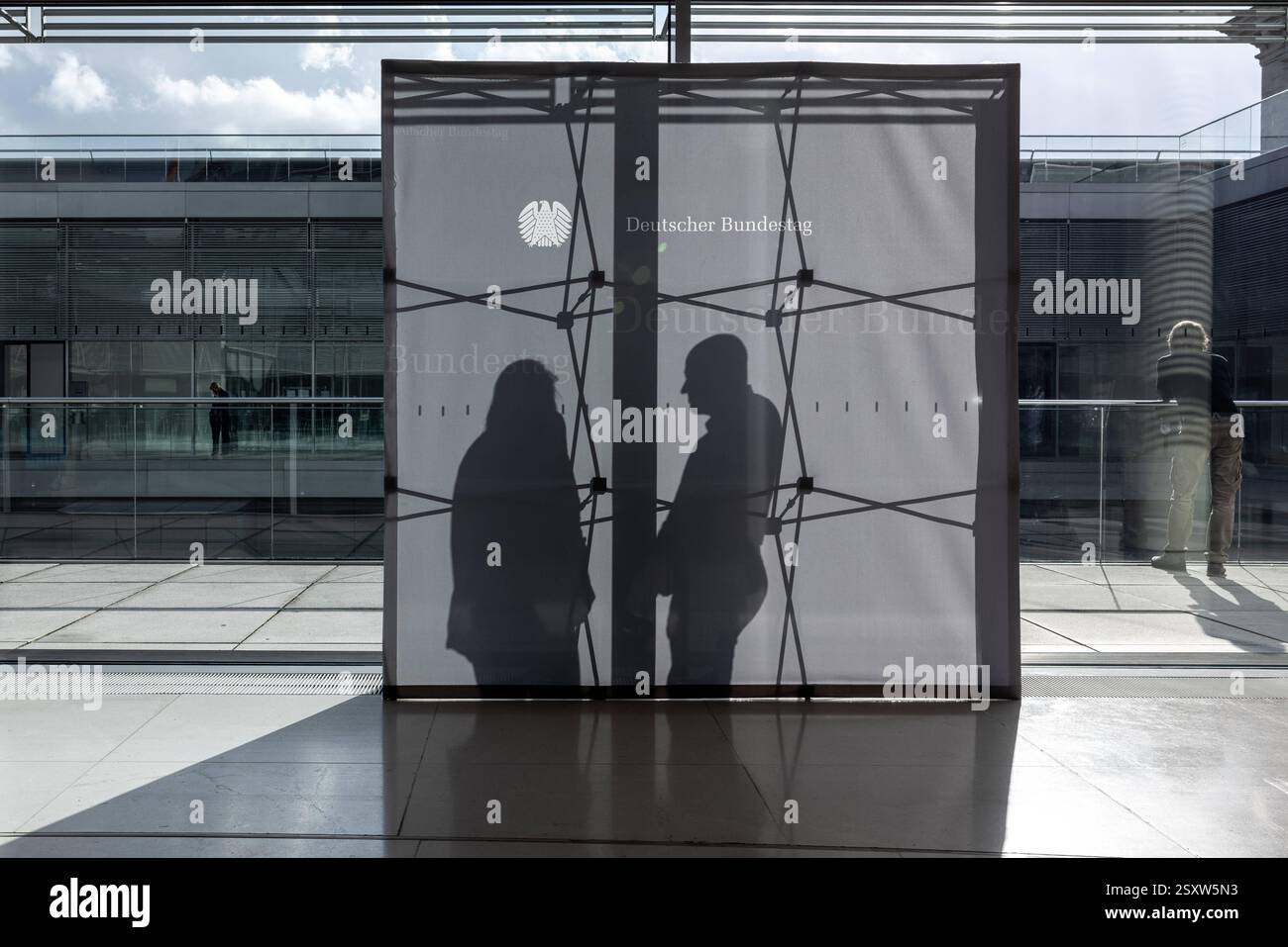 Bundestagsaufsteller auf der Fraktionsebene im Bundestag. Deutschland Berlin AM 25.02.2025: Ein grauer Aufsteller im Bundestag, der als Hintergrund für intervista Dient, Wird von der Sonne von hinten beleuchtet. Man sieht die silhouette des Gerüsts und zwei Menschen, die miteinander sprechen. *** Bundestag stand-up display a livello di gruppo parlamentare nel Bundestag Germania Berlino al 25 02 2025 Un stand-up grigio nel Bundestag, che funge da sfondo per interviste, è illuminato dal sole da dietro si può vedere la sagoma dell'impalcatura e due persone che parlano con Foto Stock