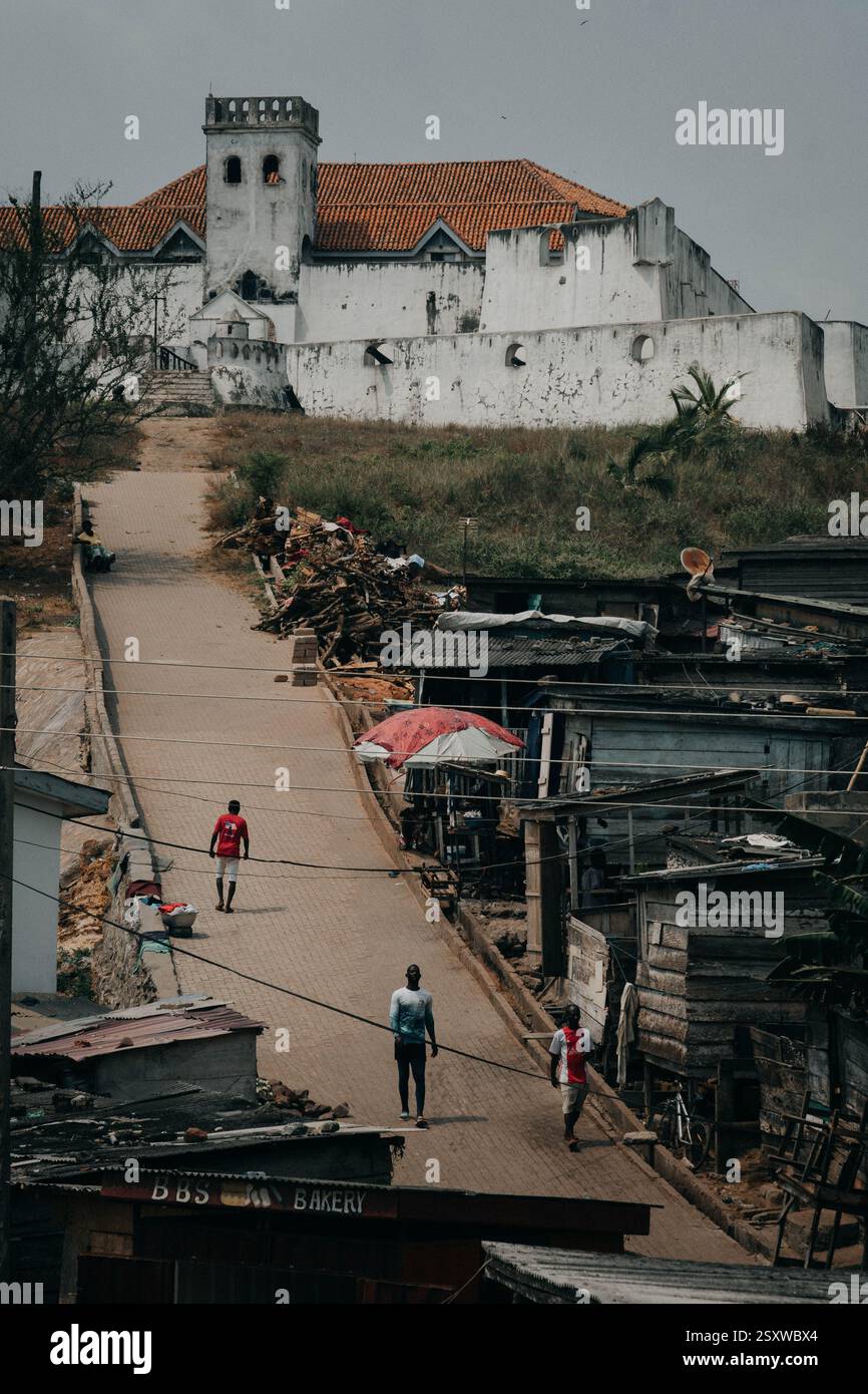 La strada che porta alla vecchia fortezza coloniale di Elmina, Ghana, una città storica dell'Africa occidentale. Foto Stock