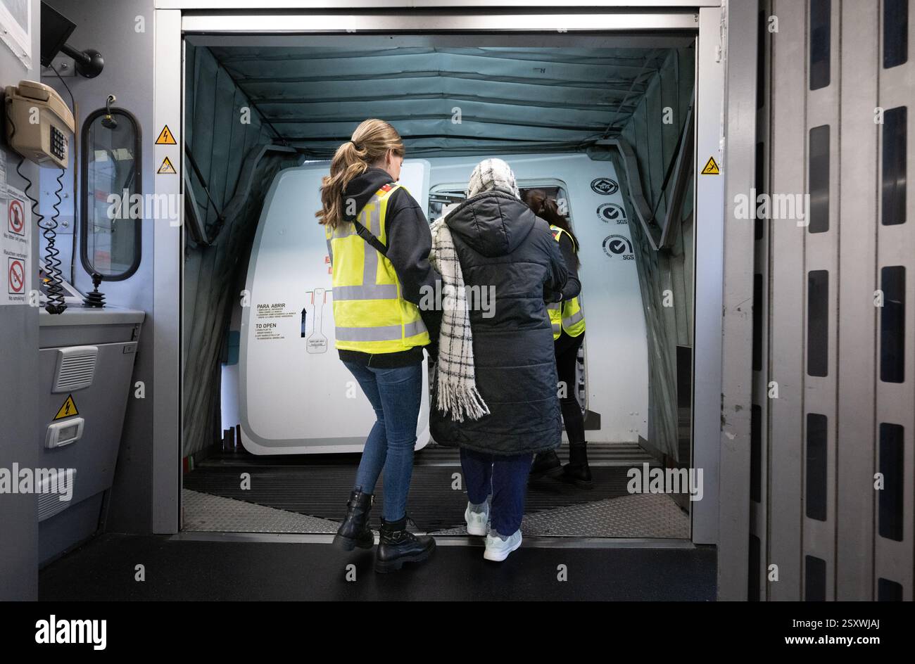 25 febbraio 2025, Assia, Francoforte sul meno: Un ufficiale della polizia federale prende una donna su un volo di deportazione in Pakistan. Foto: Boris Roessler/dpa Foto Stock