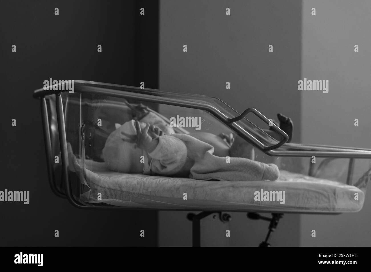 Un momento toccante di parto in un ospedale. I medici e il personale assistono la madre mentre il padre condivide la gioia dei primi momenti del neonato. Foto Stock