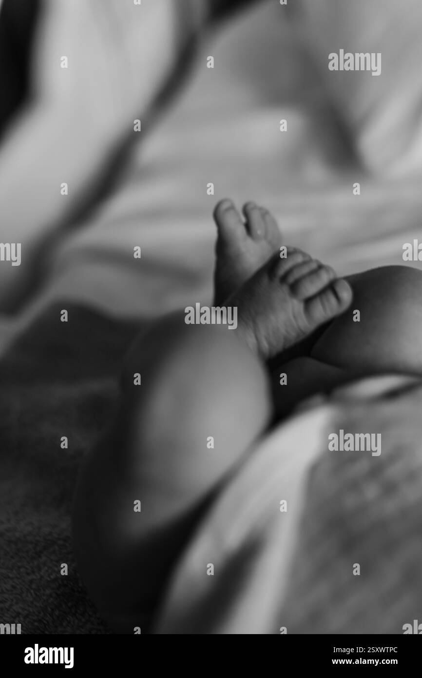 Un momento toccante di parto in un ospedale. I medici e il personale assistono la madre mentre il padre condivide la gioia dei primi momenti del neonato. Foto Stock