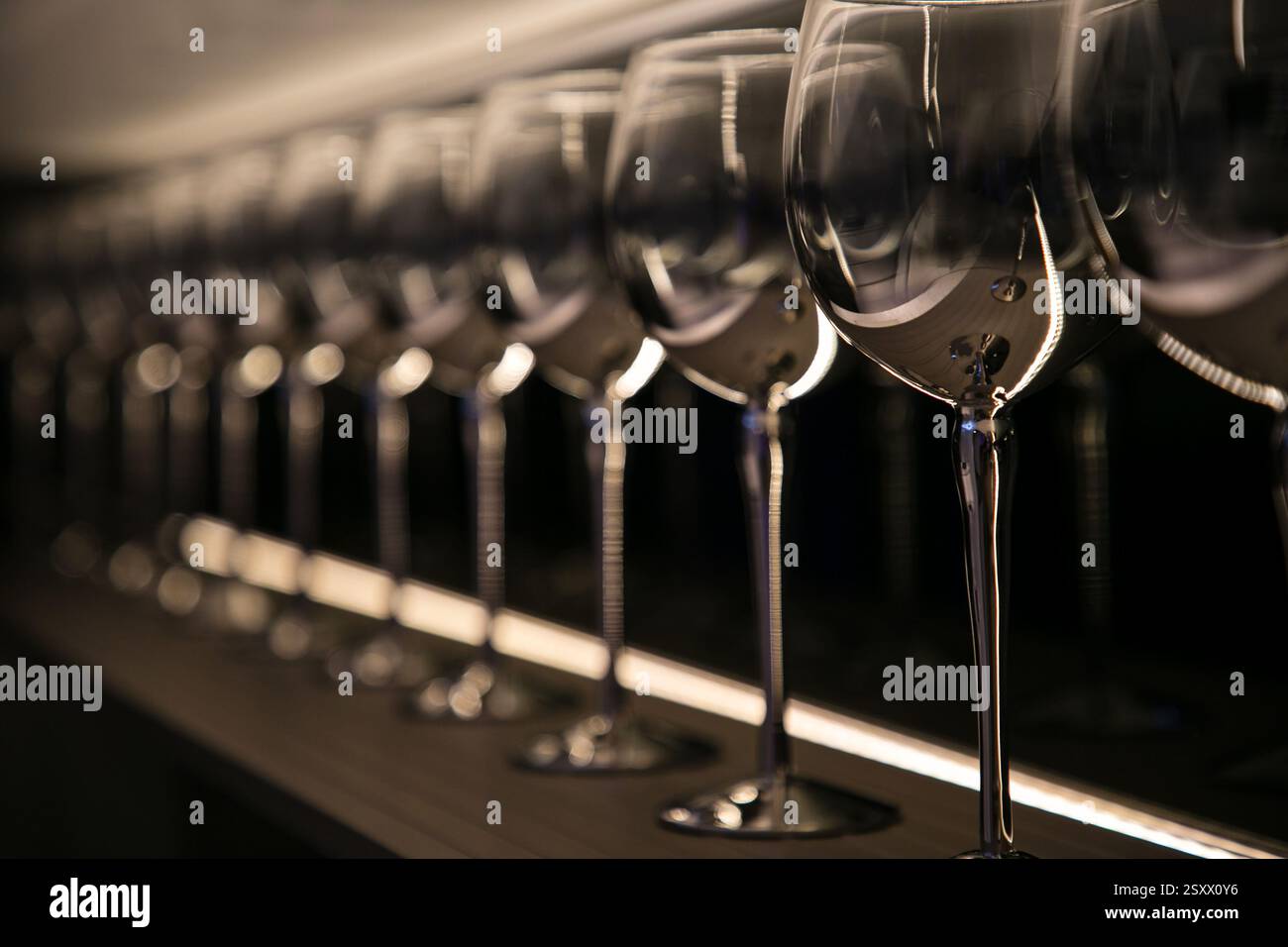 Elegante linea di bicchieri da vino illuminati su un moderno banco bar Foto Stock