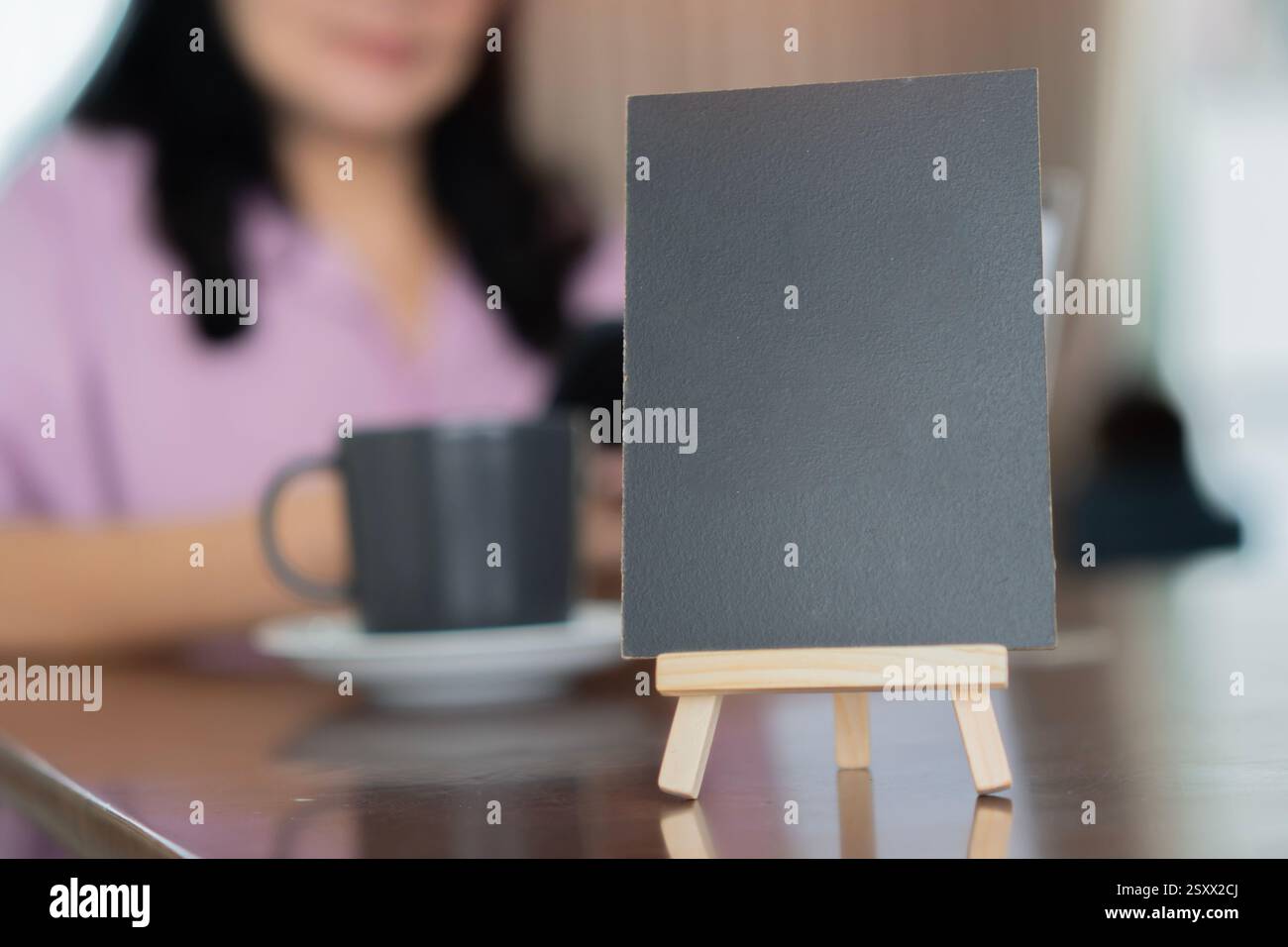 Menu' con cornice di legno in piedi su un tavolo di legno nel Bar Restaurant Cafe con donna sfocata dietro. Spazio per la promozione di marketing testuale Foto Stock