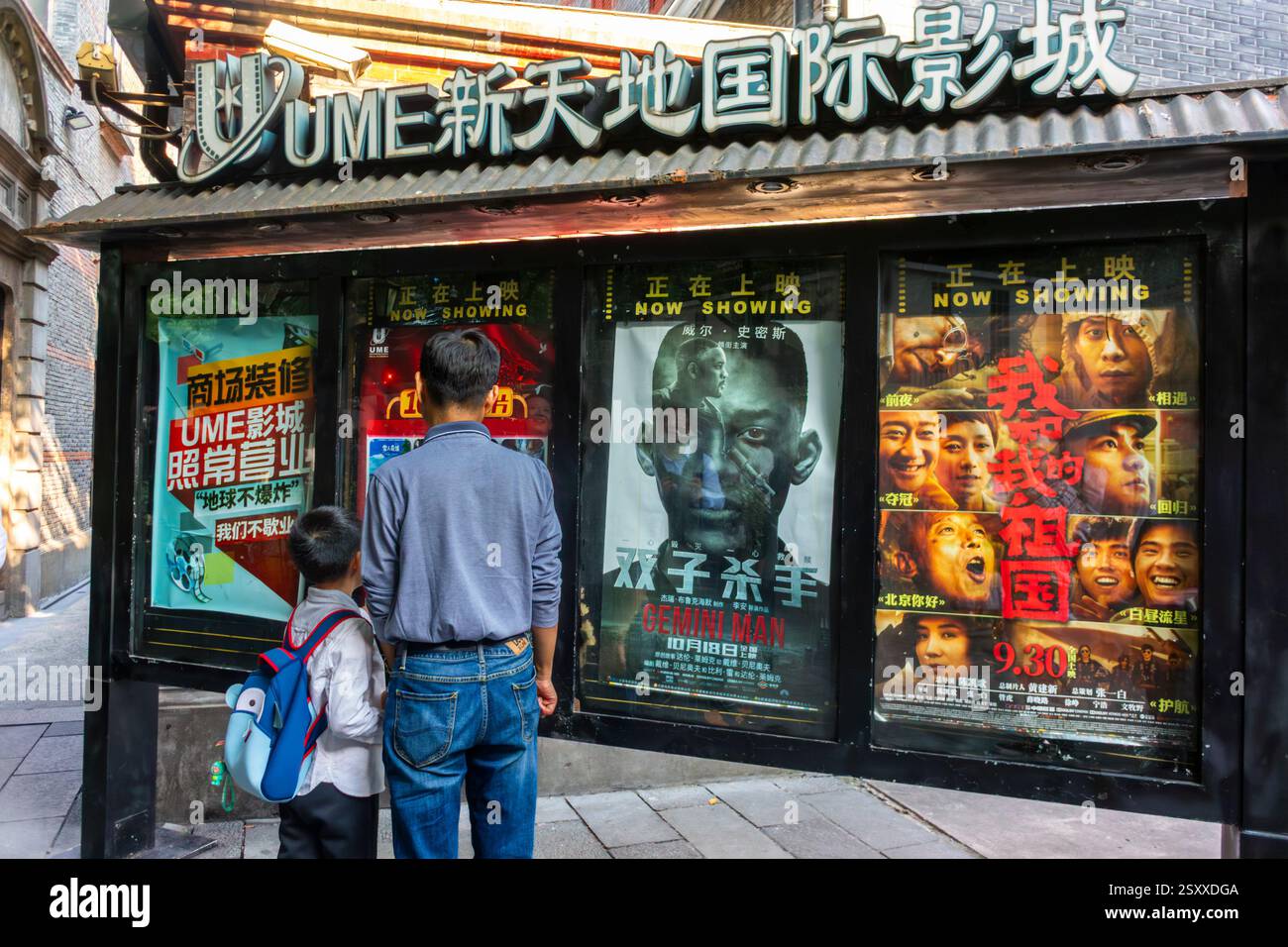 Shanghai, Cina, primo piano, esporre poster del cinema cinese a muro, scena di strada, esterno, papà e figlio che guardano da dietro il pannello, politica per un figlio Foto Stock