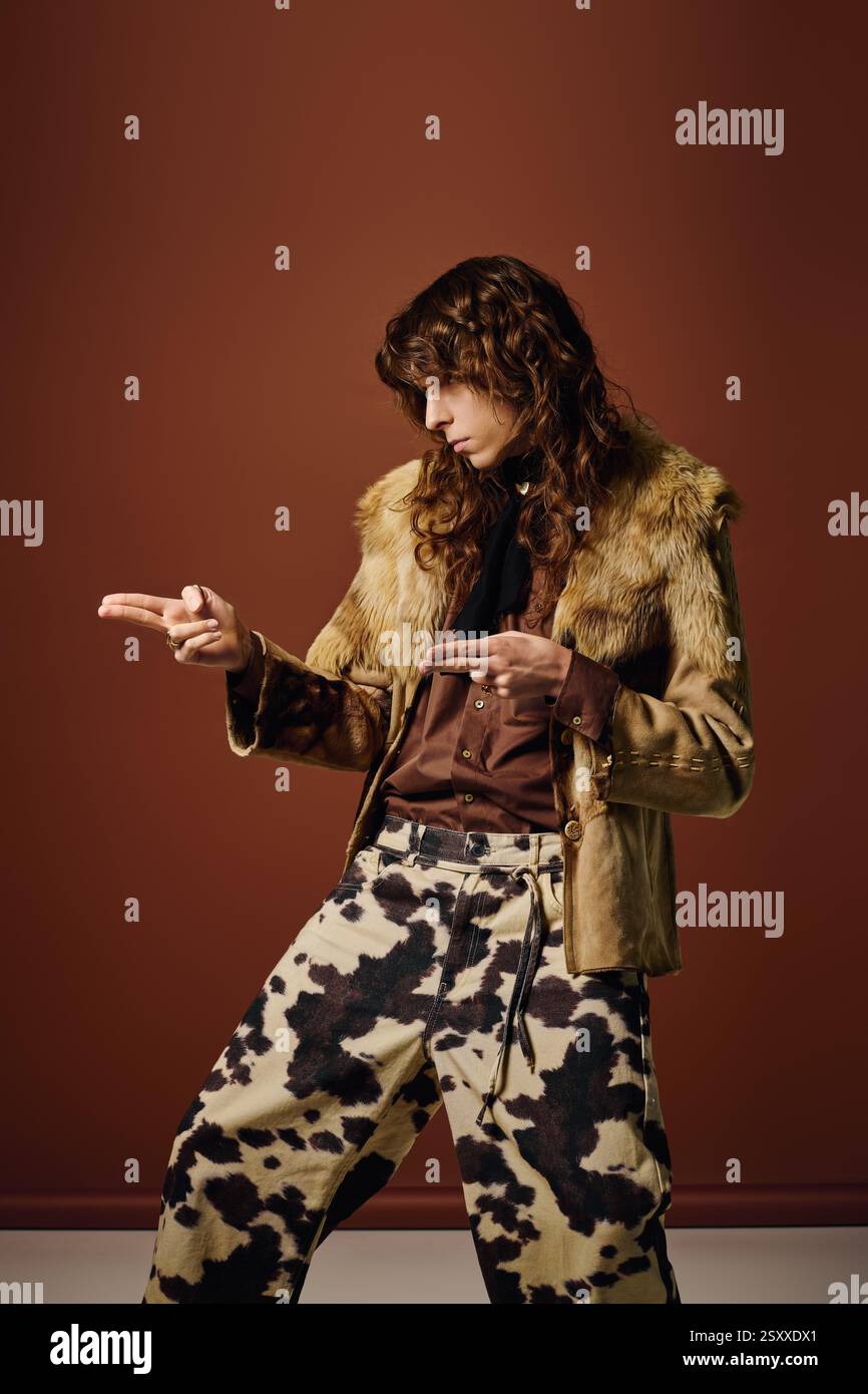 Un bell'uomo posa con sicurezza, indossando una giacca in pelliccia e pantaloni fantasia con un tocco creativo. Foto Stock
